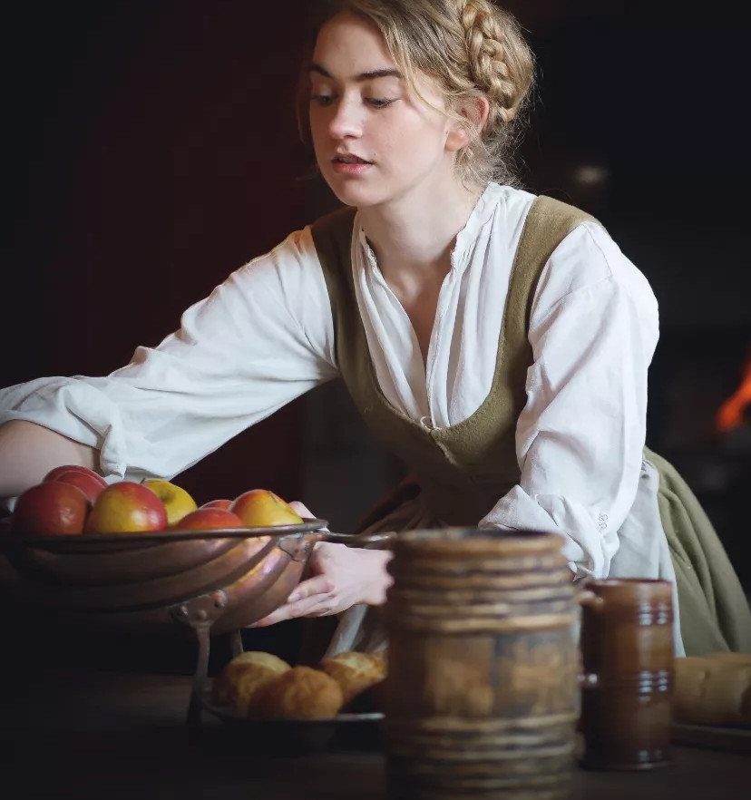 16th Century Fashion for Women: 9 Gown and Bodice Ideas 1 Woman in period clothing holding a bowl of apples in a rustic kitchen