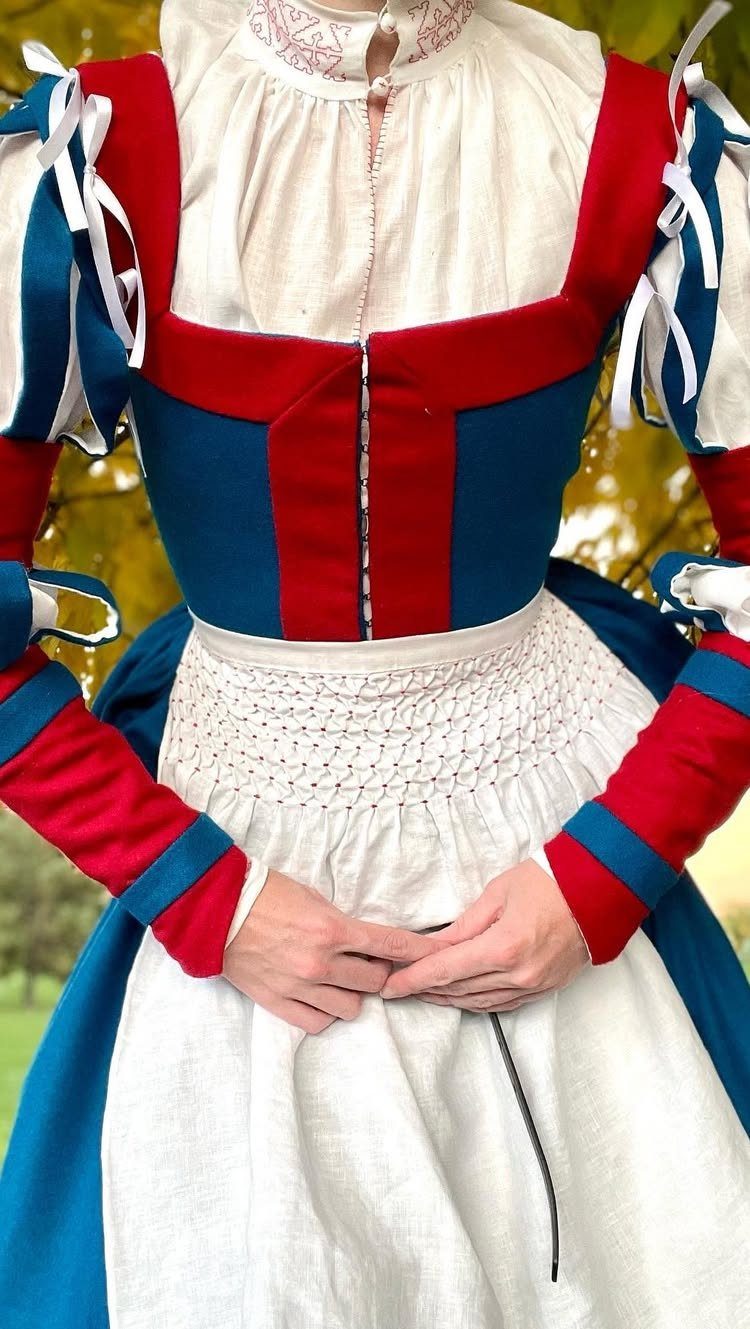 16th Century Fashion for Women: 9 Gown and Bodice Ideas 9 Woman wearing a red and blue 16th century style bodice and white apron