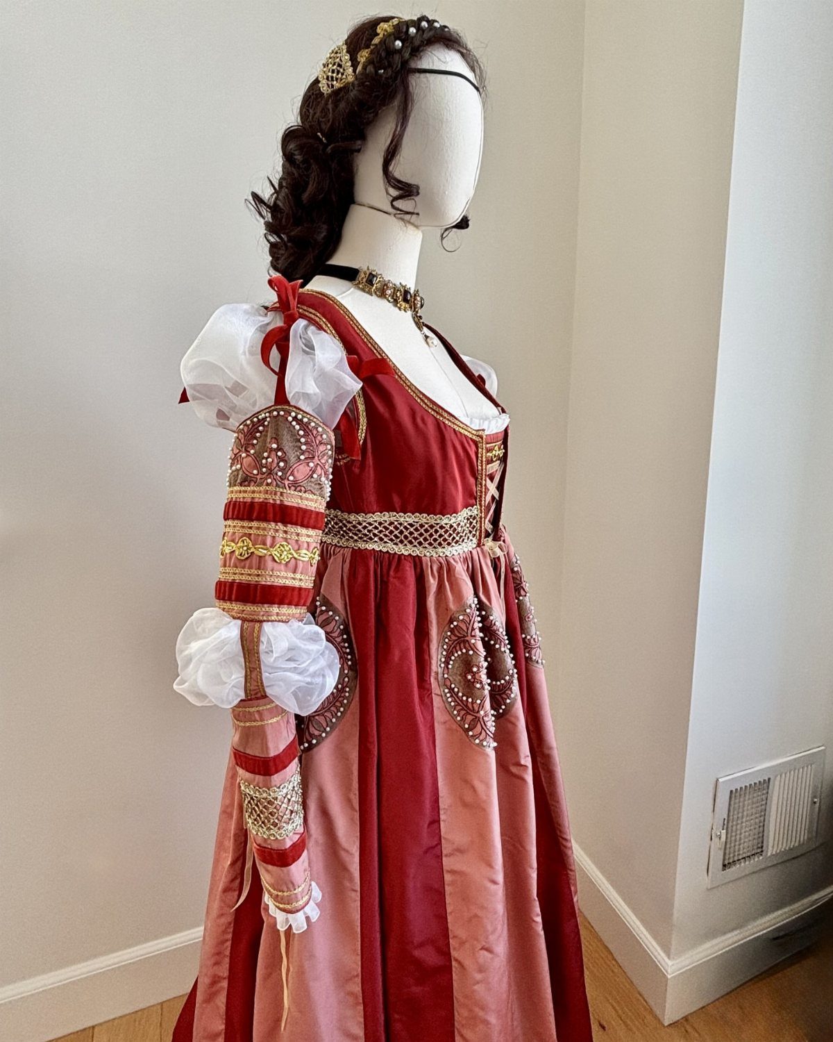 16th Century Fashion for Women: 9 Gown and Bodice Ideas 5 Mannequin wearing a red and pink 16th century style gown with gold embroidery.