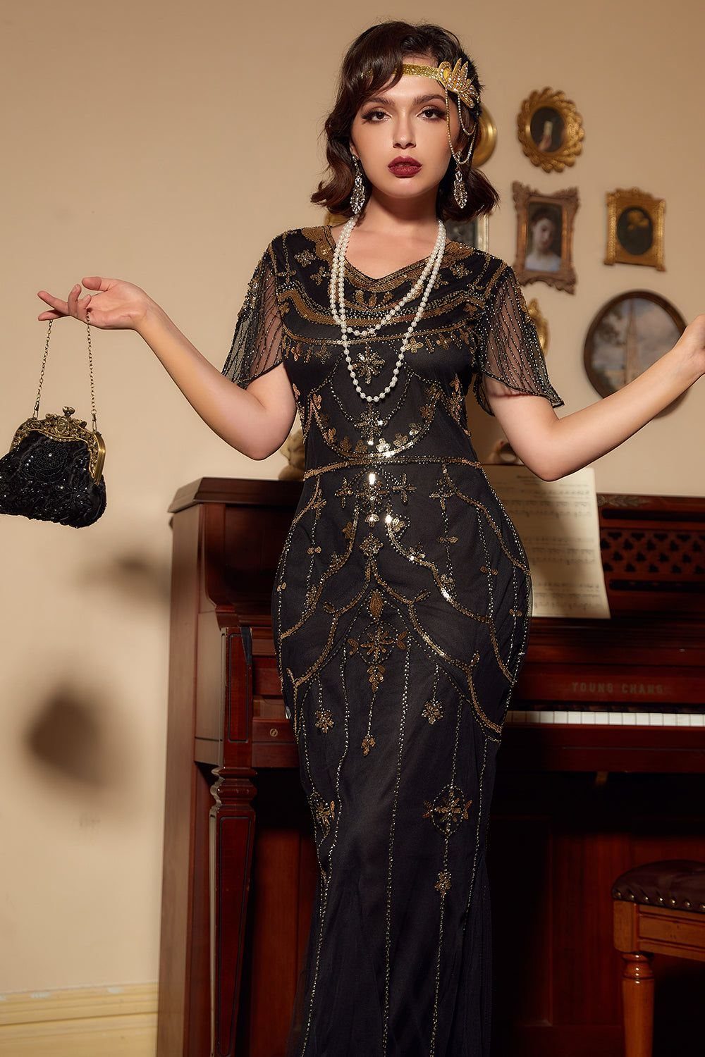 Woman in a black gold-sequined 1920s gown with pearls and a gold headband.