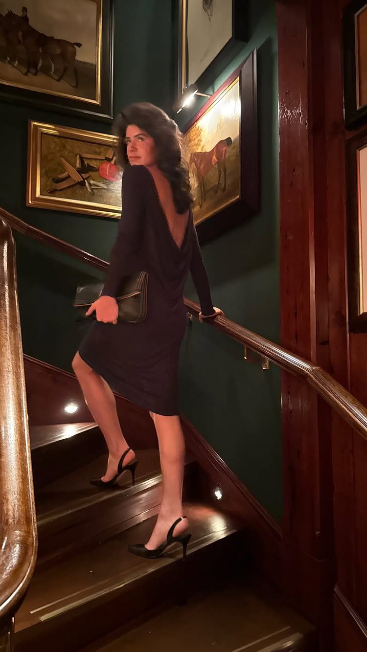 Woman in a purple 80s evening dress with big hair on wooden stairs