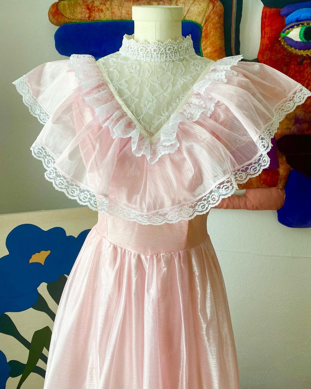 Light pink evening dress with lace ruffles and high collar on a mannequin