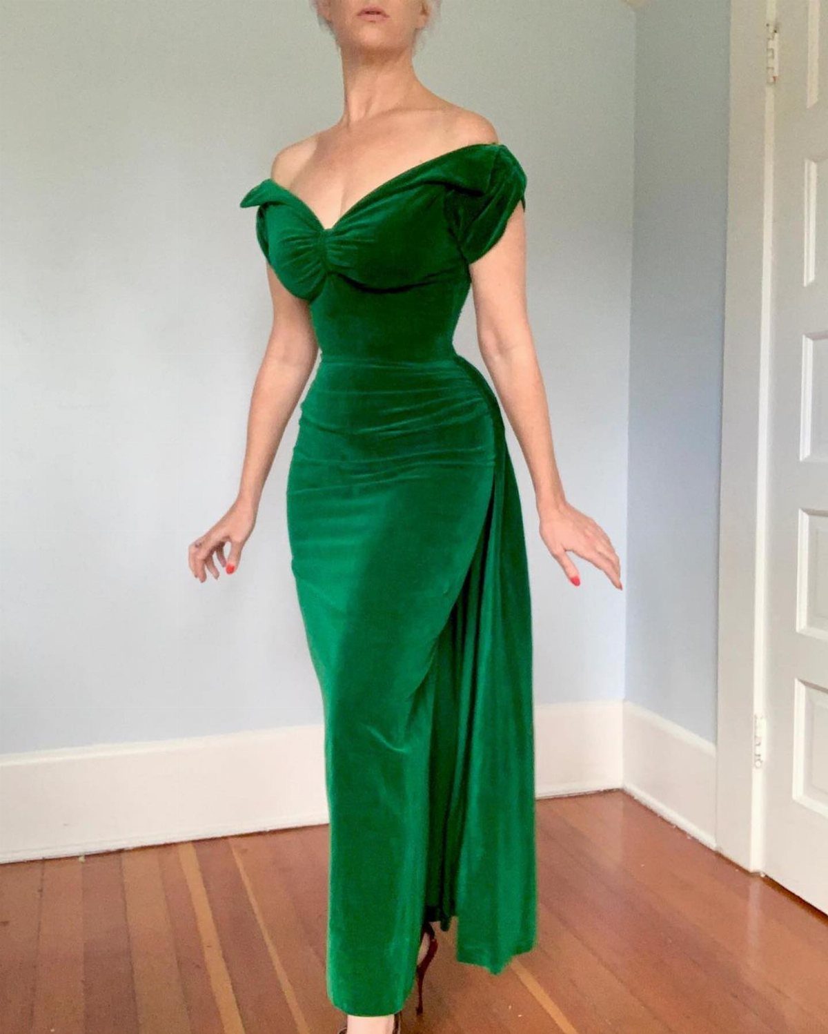 Woman in a long emerald green velvet evening gown with off-the-shoulder neckline.