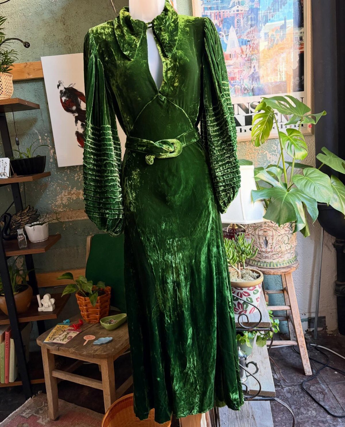 Emerald green velvet evening dress with puffed sleeves and belt on a mannequin