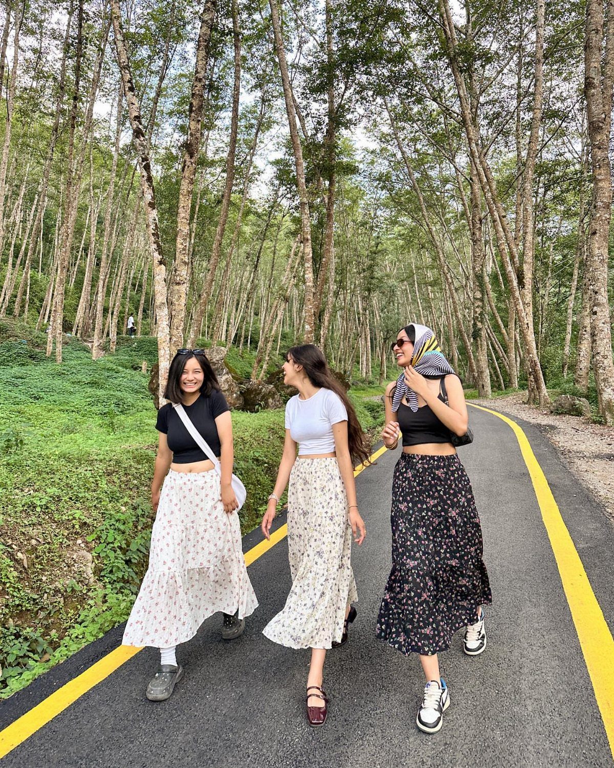 90s Skirt Outfits: 7 Ideas, from Floral Maxi to Mini 1 Three women wearing floral maxi skirts walking along a road in a forest.
