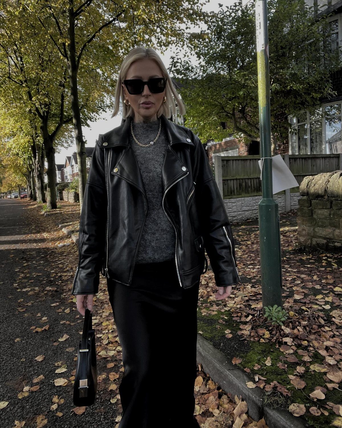 90s Skirt Outfits: 7 Ideas, from Floral Maxi to Mini 6 Woman in oversized leather jacket and long black skirt standing on autumn sidewalk