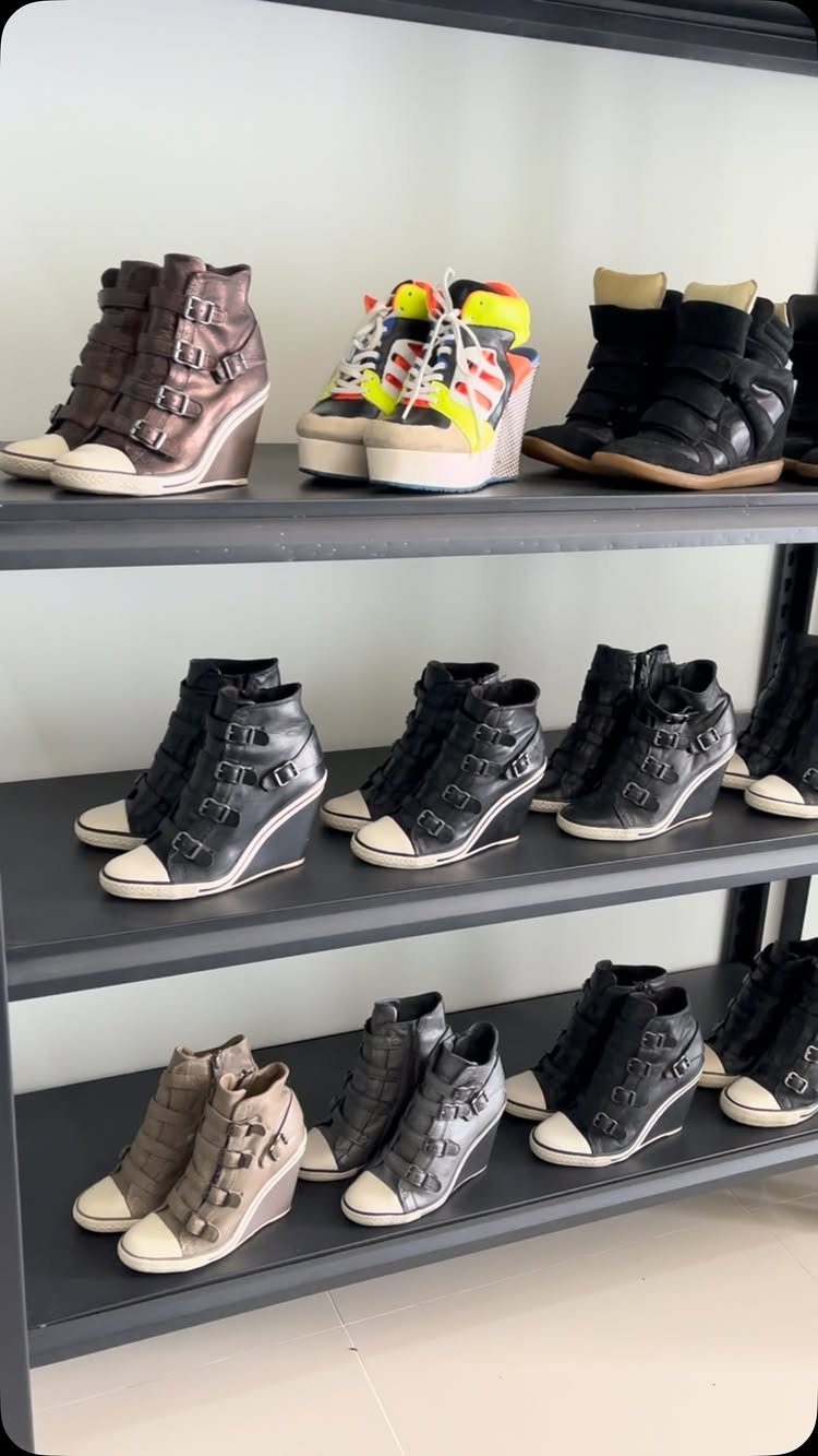 Adidas Superstar Up Wedge with 5 Outfit Ideas to Copy 1 Wedge sneakers in various colors displayed on black shelving units against white wall.