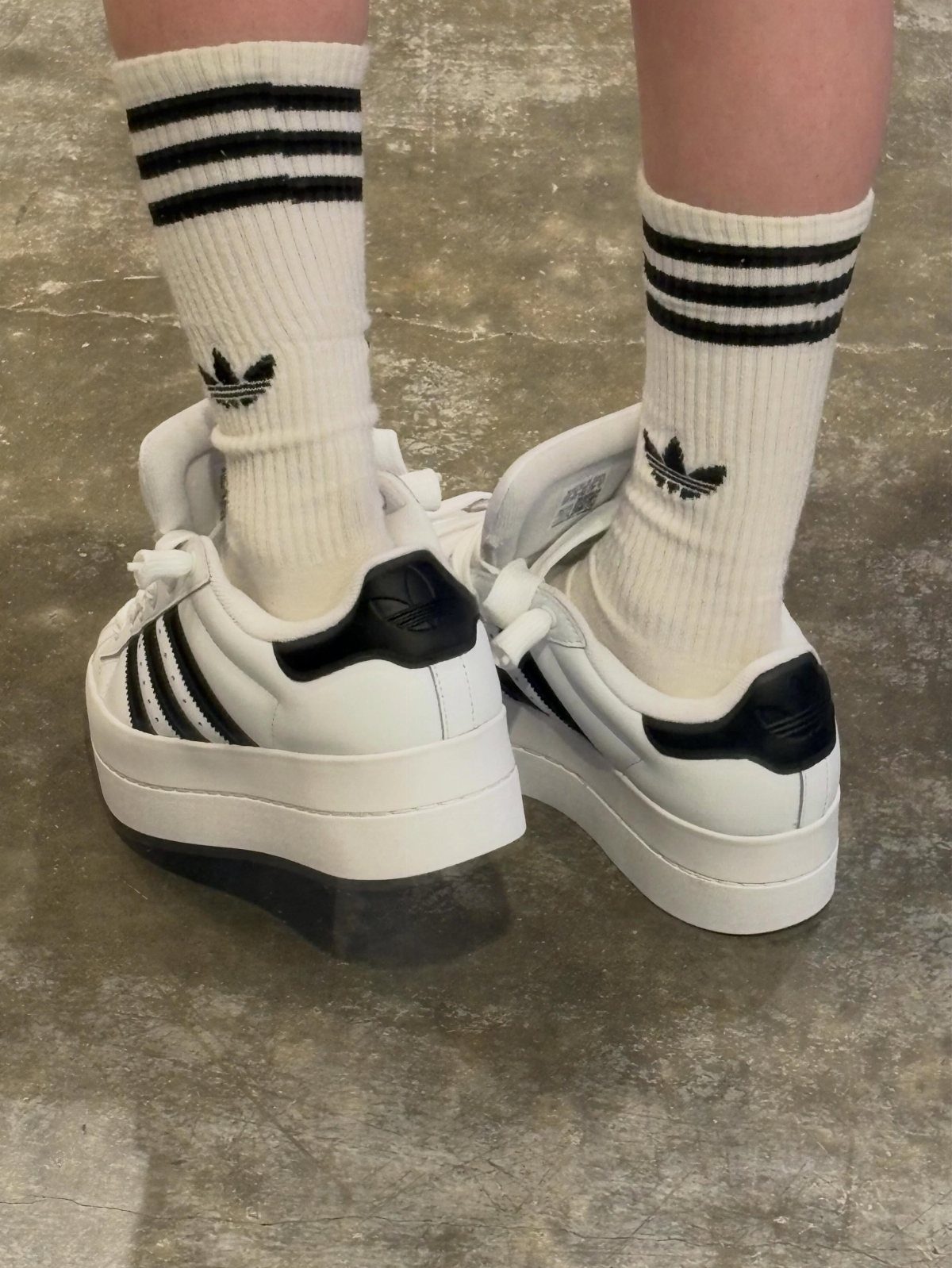 Adidas Superstar Up Wedge with 5 Outfit Ideas to Copy 5 White Adidas Superstar wedge sneakers and matching striped crew socks on a concrete floor