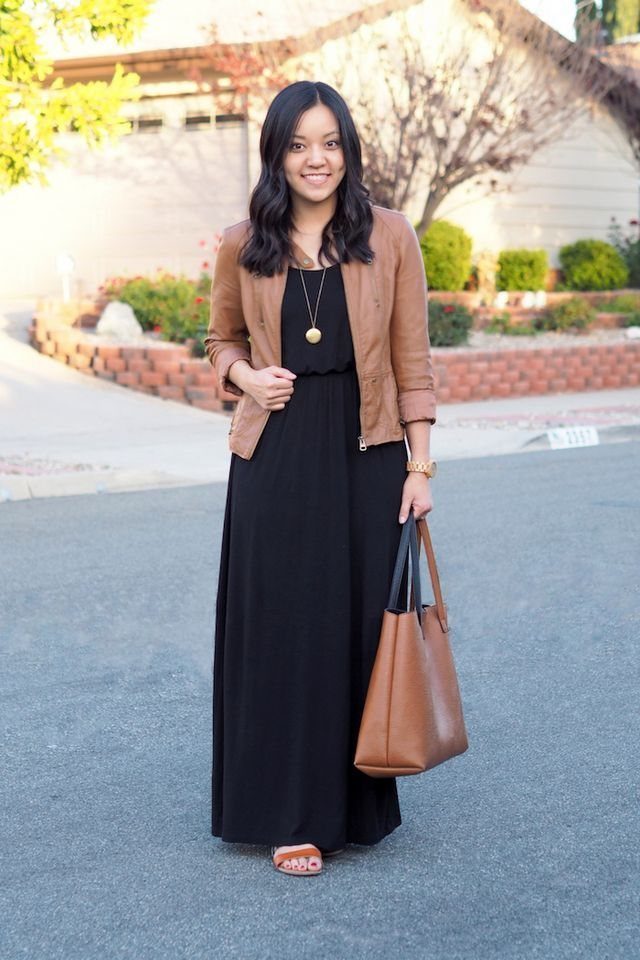 Woman wearing a black maxi dress paired with a brown leather jacket and tote.