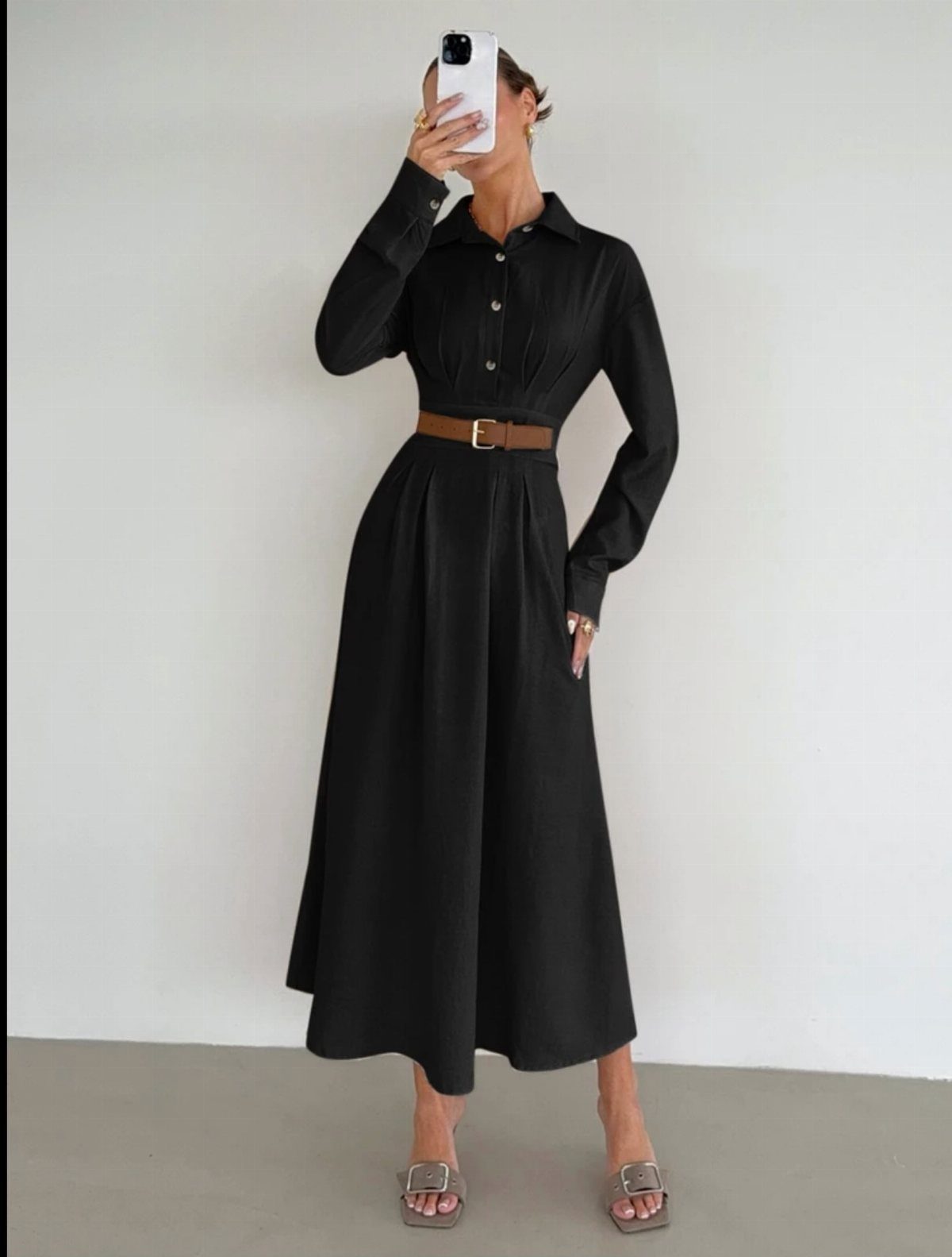 Woman wearing a black midi shirt dress with a brown belt and sandals.