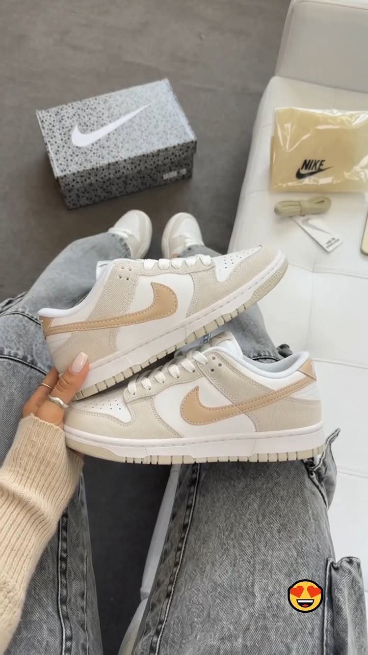 Beige Nike Dunk Low sneakers worn with grey denim jeans on white background