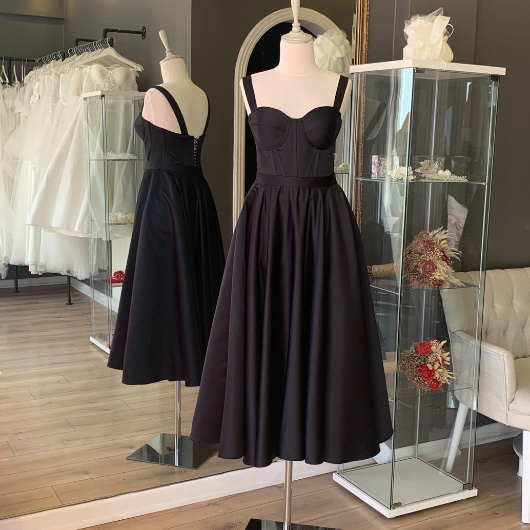 Black midi dresses with full skirts displayed on mannequins in a bridal boutique.