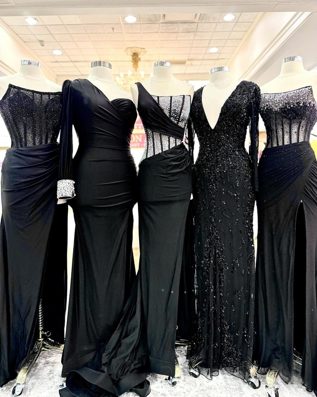 6 Black Dress Design Ideas for Formal and Wedding Looks 1 Five black formal gowns on mannequins showcasing different elegant evening dress designs.