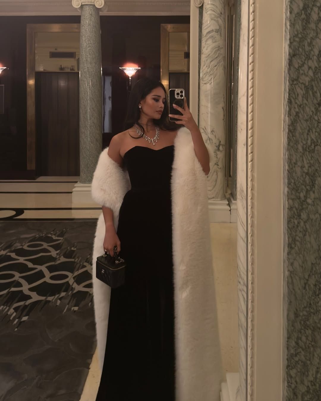 Woman in strapless black bodycon dress with a long white faux fur stole.