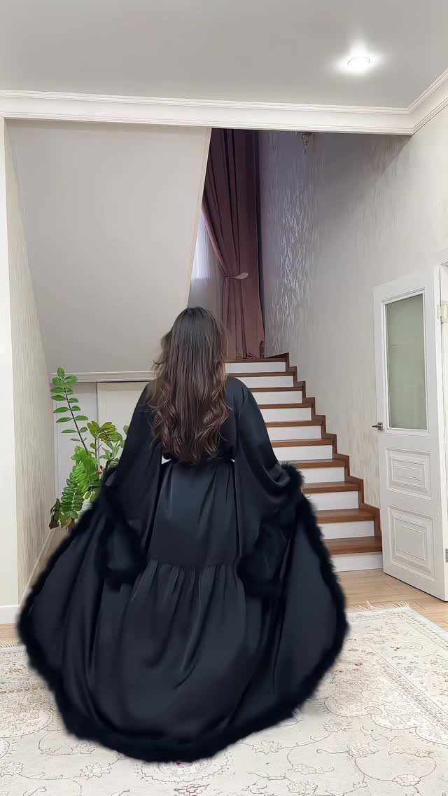 Woman from behind in a long black dress with black fur trim.