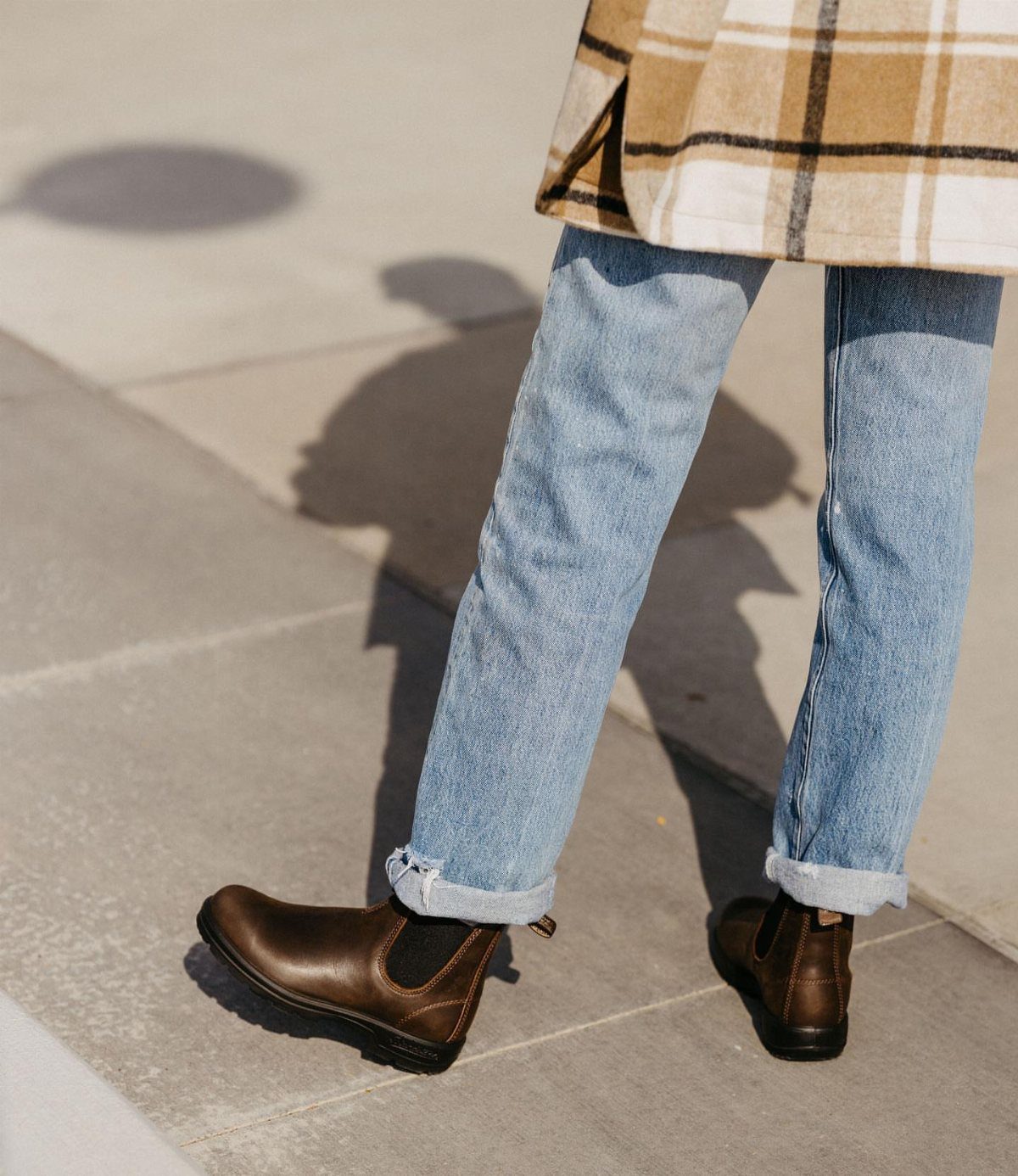 Black or Brown Boots for Every Outfit: 8 Ideas to Wear 5 Dark brown leather Chelsea boots paired with cuffed light blue jeans on concrete.