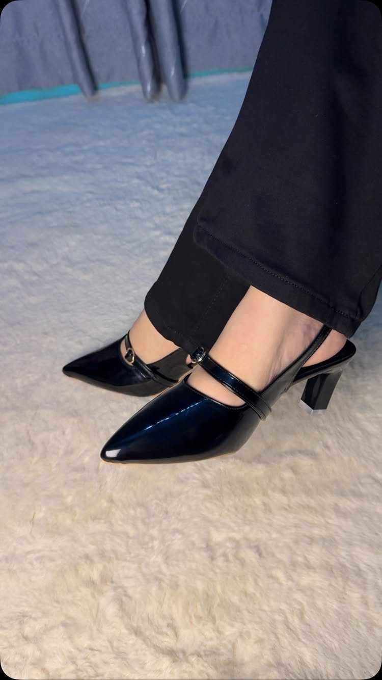 Black patent leather slingback pumps with low block heels and pointed toes.