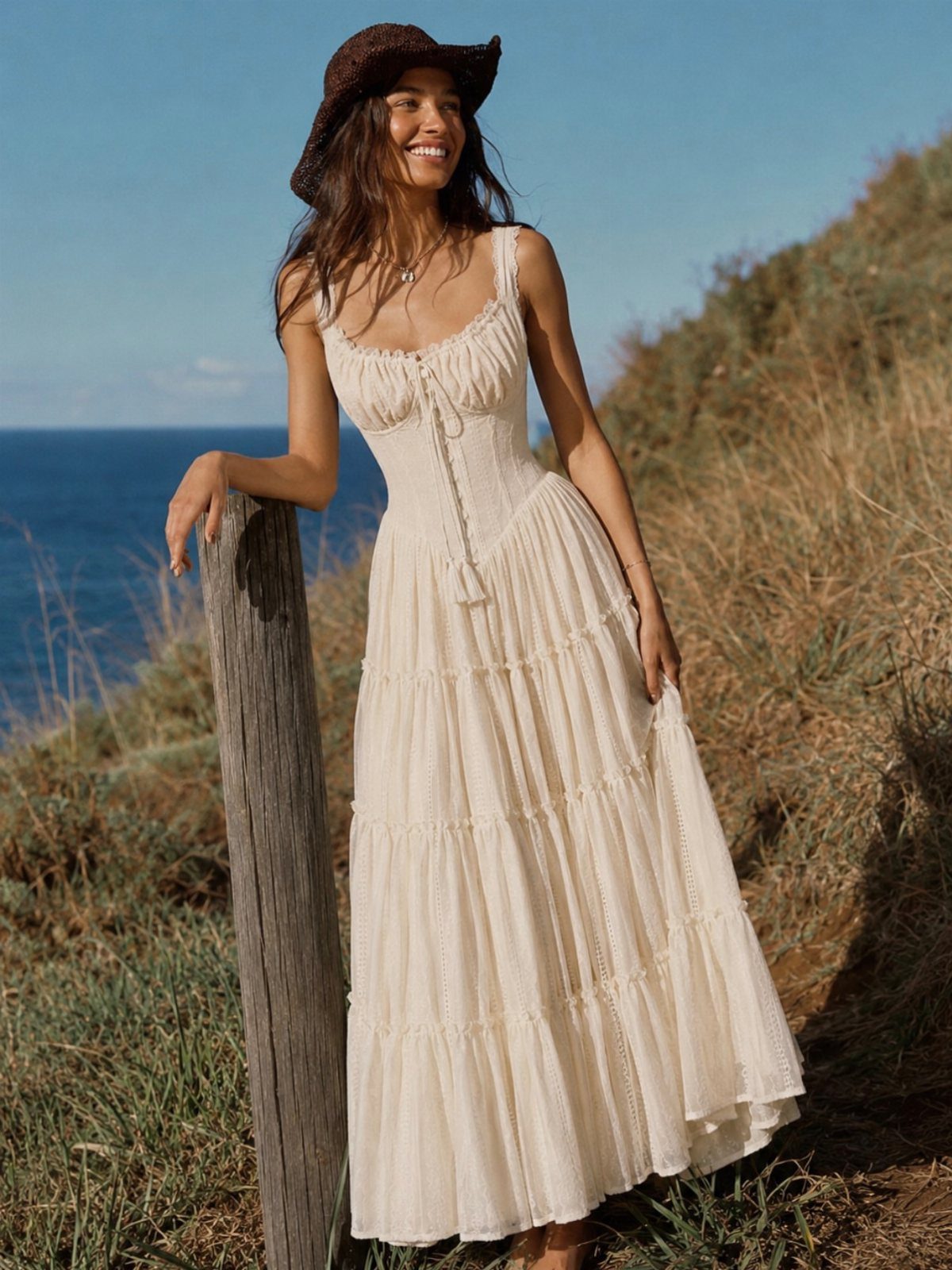 Bohemian Cream Dress Ideas: 9 Ways to Wear One 2 Woman in a cream crochet and ruffled maxi dress posing on a coastal cliff