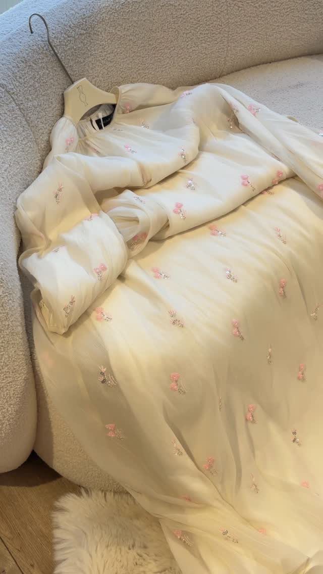 Bohemian Cream Dress Ideas: 9 Ways to Wear One 7 Cream long-sleeved dress with pink floral embroidery draped over a grey sofa.