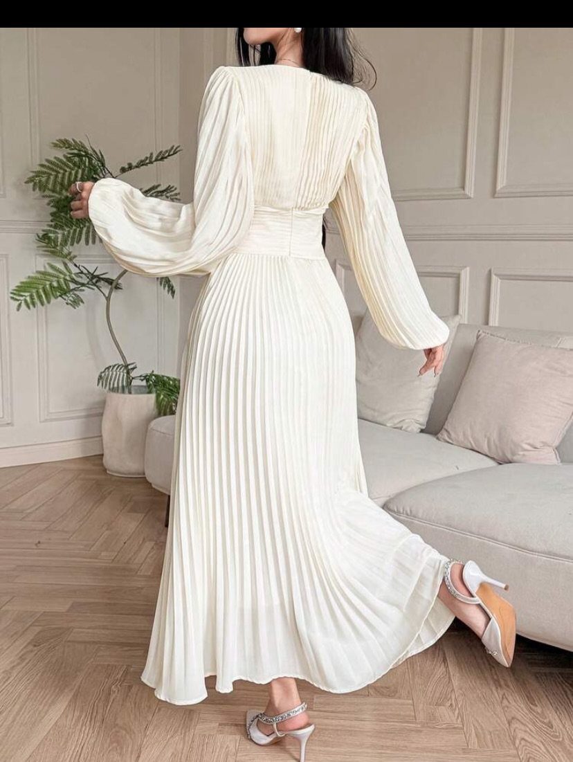 Bohemian Cream Dress Ideas: 9 Ways to Wear One 6 Woman wearing a pleated cream maxi dress with long sleeves in a bright room