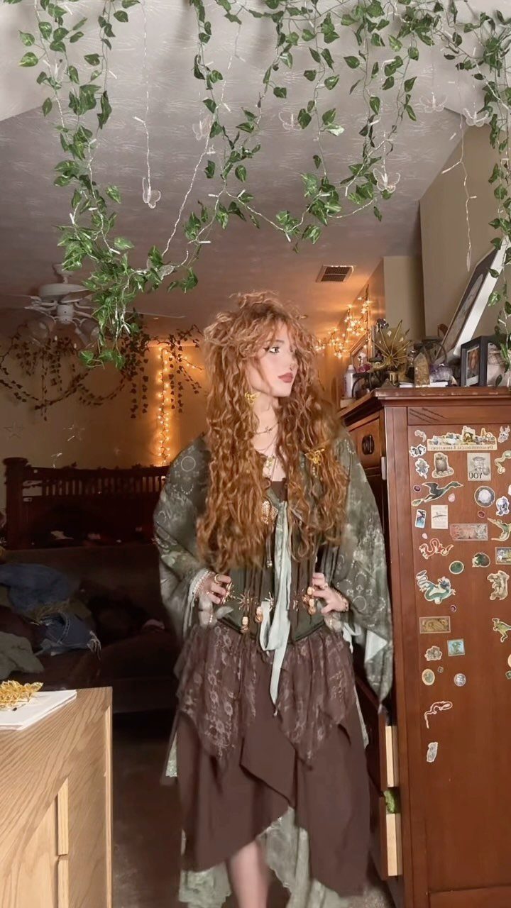 Woman with curly red hair wearing olive green and brown boho grunge clothing.
