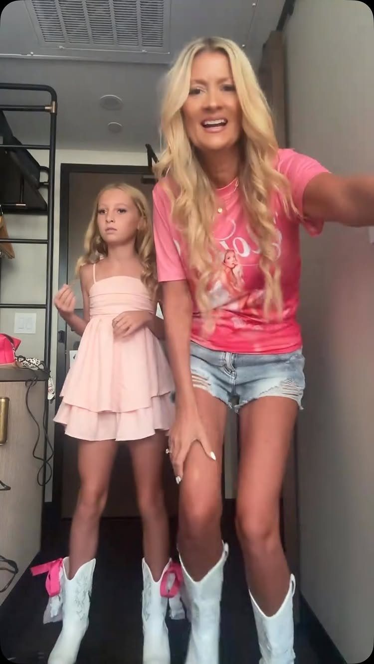 Woman and girl wearing white cowboy boots with pink bows in a hallway.