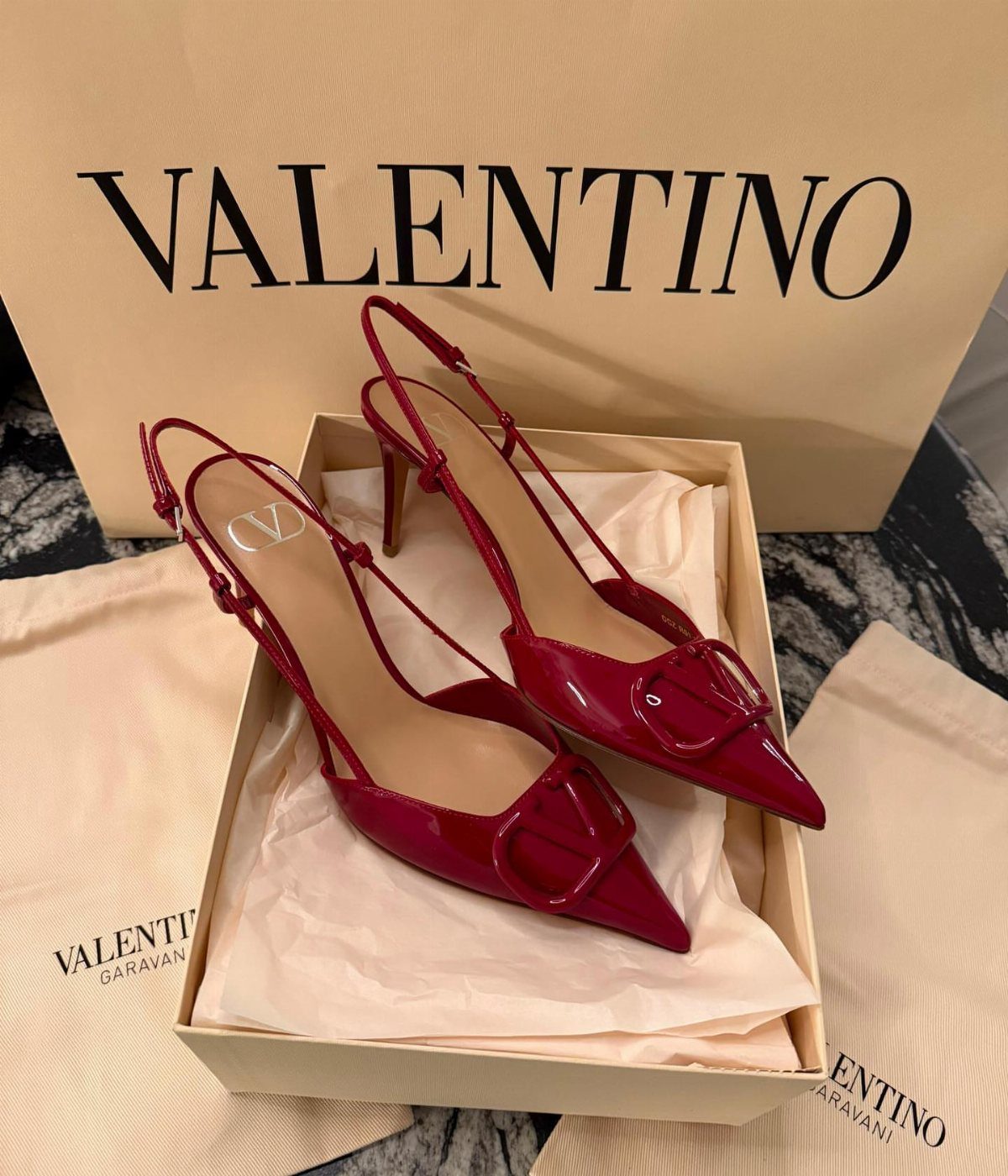 Red Valentino patent leather high heels in a beige shoebox with shopping bag
