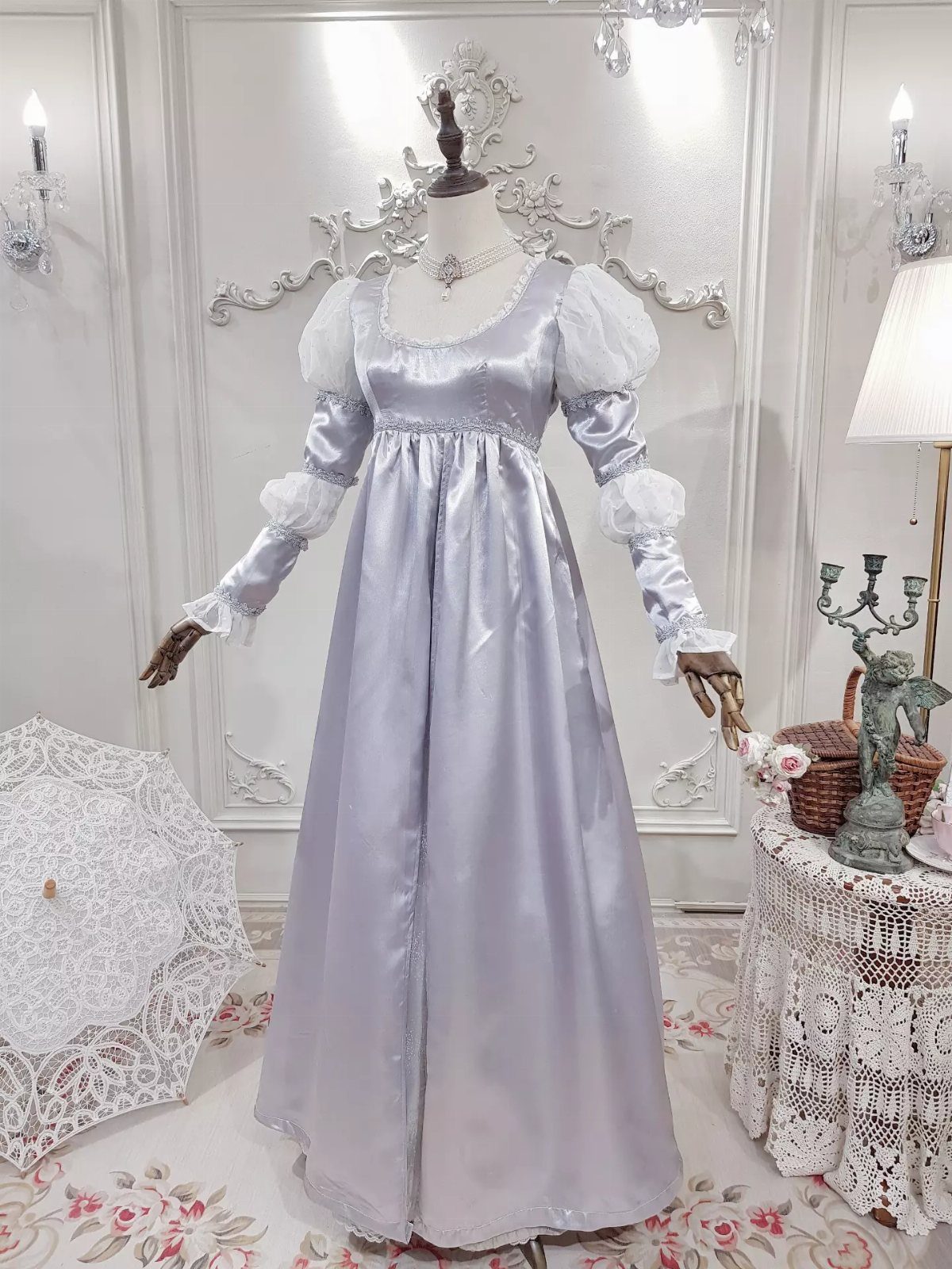 Light purple satin empire waist gown with white puffed sleeves on a mannequin.