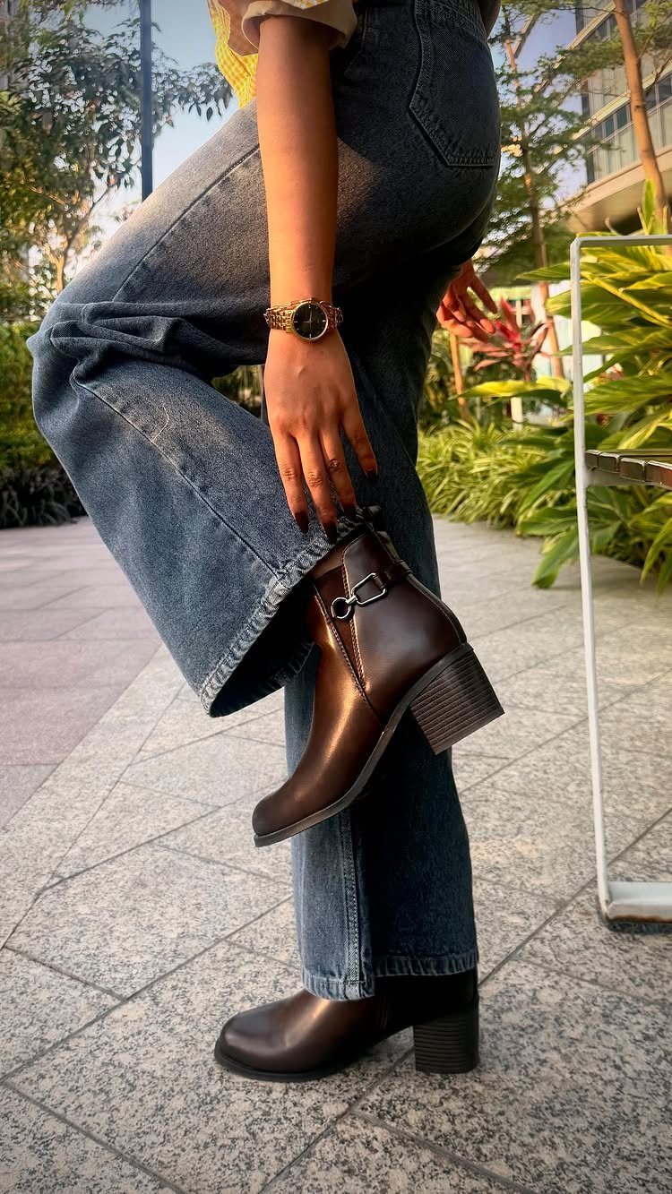 Dark brown leather ankle boots with block heels paired with wide-leg blue jeans.