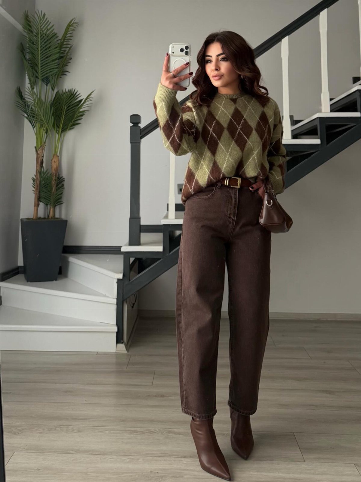 Woman wearing an argyle brown sweater and dark brown denim jeans with boots.