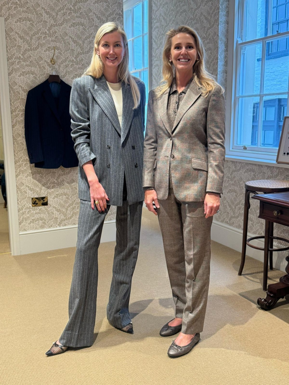Career Fair Outfits for Women: 8 Ideas to Wear 1 Two women wearing professional tailored trousers and matching blazers in a bright room.