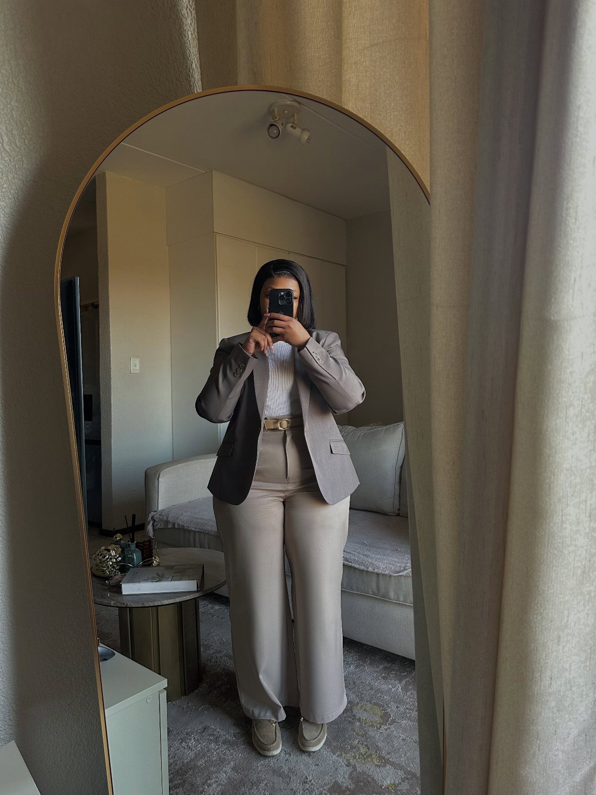 Career Fair Outfits for Women: 8 Ideas to Wear 4 Woman in a taupe blazer and beige wide-leg trousers taking a mirror selfie.