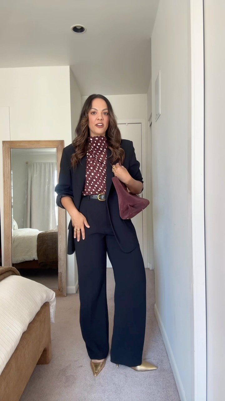 Career Fair Outfits for Women: 8 Ideas to Wear 6 Woman wearing a navy blue suit with a polka dot blouse and gold heels.