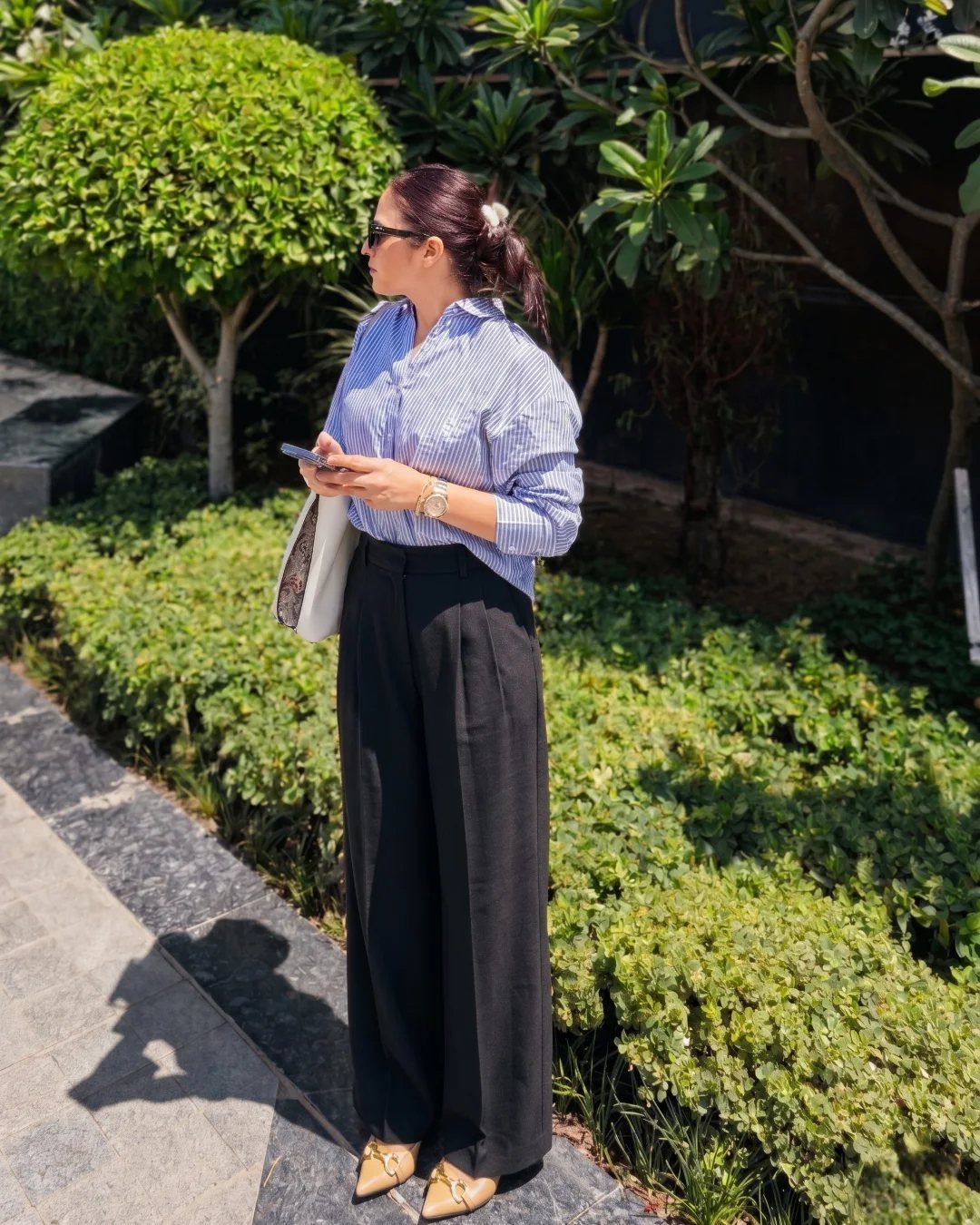 Career Fair Outfits for Women: 8 Ideas to Wear 5 Woman wearing wide-leg black tailored trousers and a striped blue shirt outdoors.