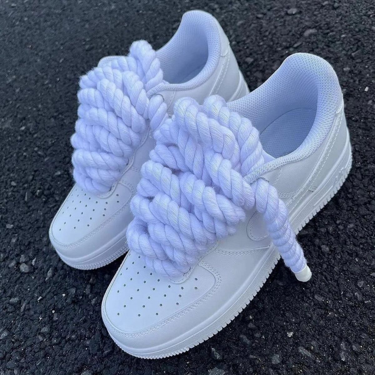 White leather sneakers with thick braided white cotton rope laces on asphalt
