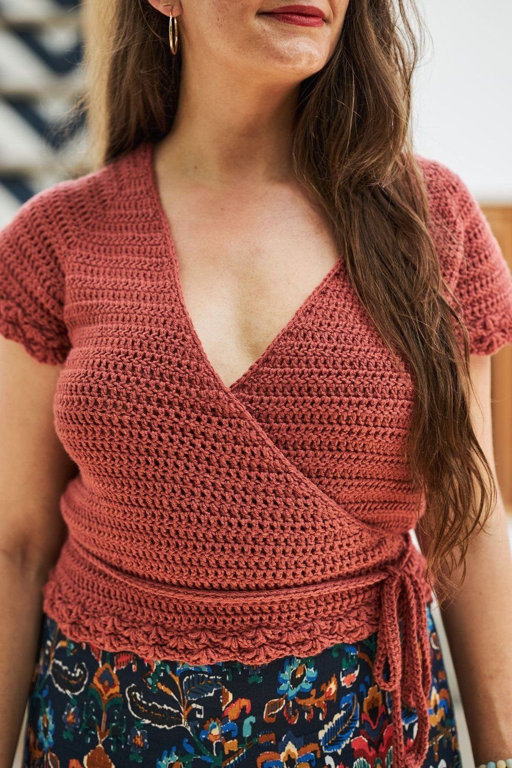 Terracotta crochet wrap top with scalloped hem worn by a woman.