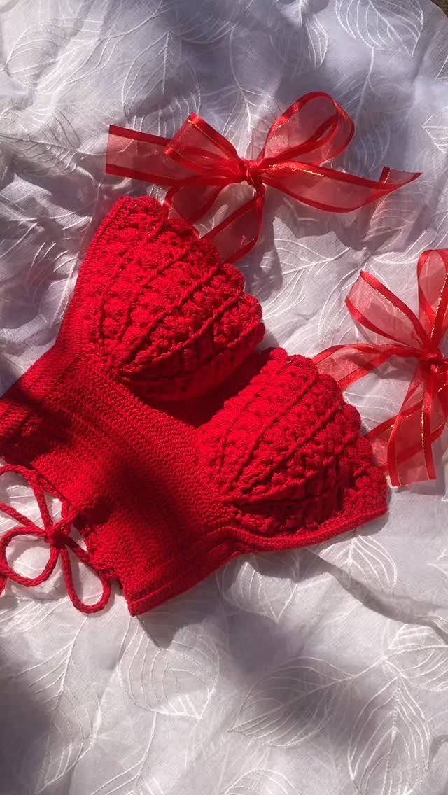 Red crochet crop top with ribbon ties on a white textured background