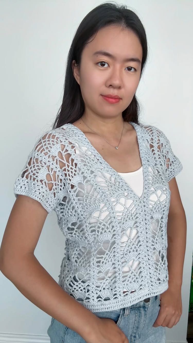 Woman wearing a light blue crochet lace V-neck top and blue jeans.