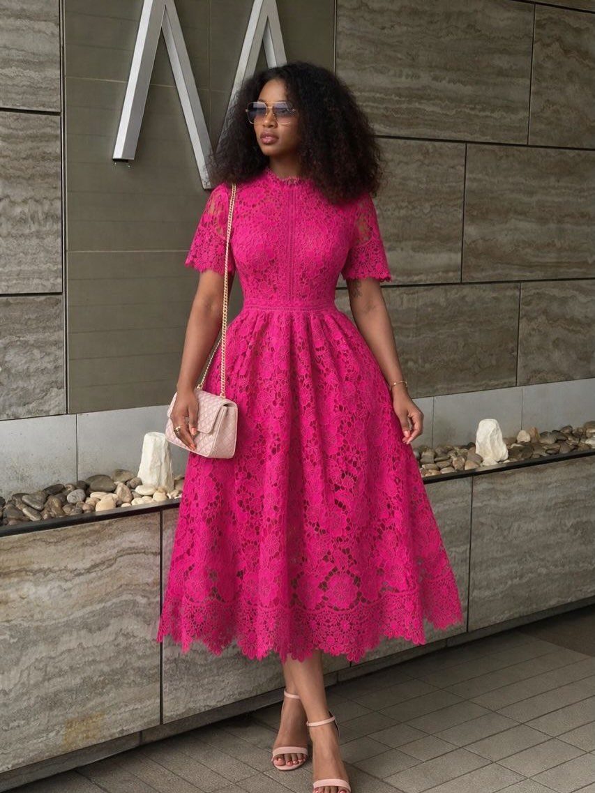 Woman in a bright pink lace fit-and-flare midi dress and nude heels.