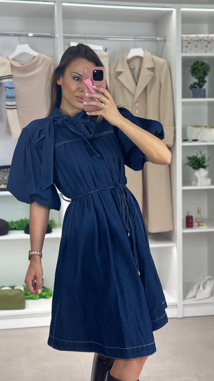 Woman wearing a dark blue denim dress with a matching waist tie belt.