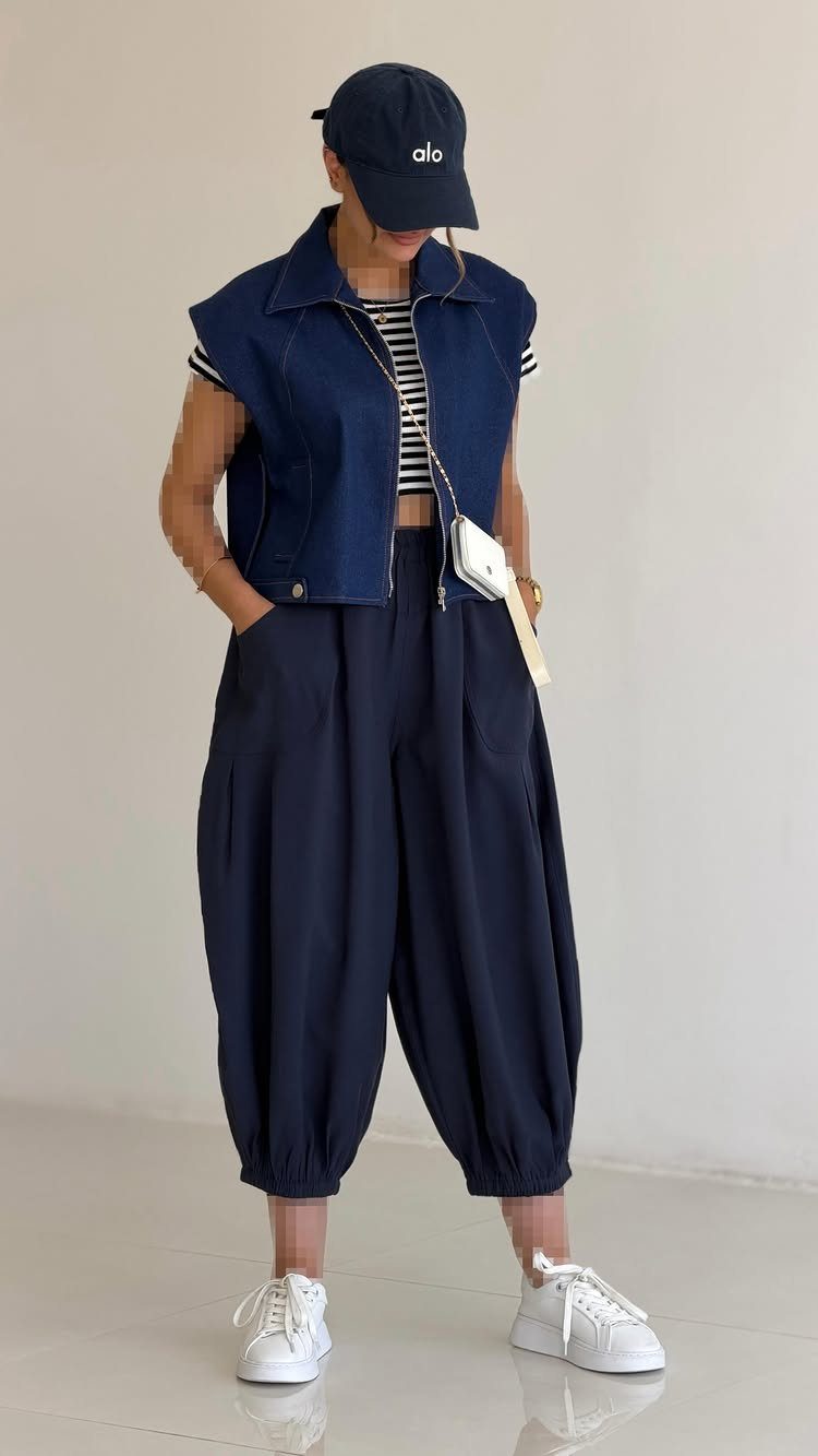 Person wearing a dark blue denim vest and baggy navy harem pants.