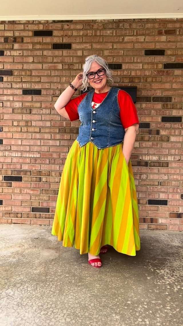 Woman wearing a blue denim vest and a yellow striped maxi skirt.