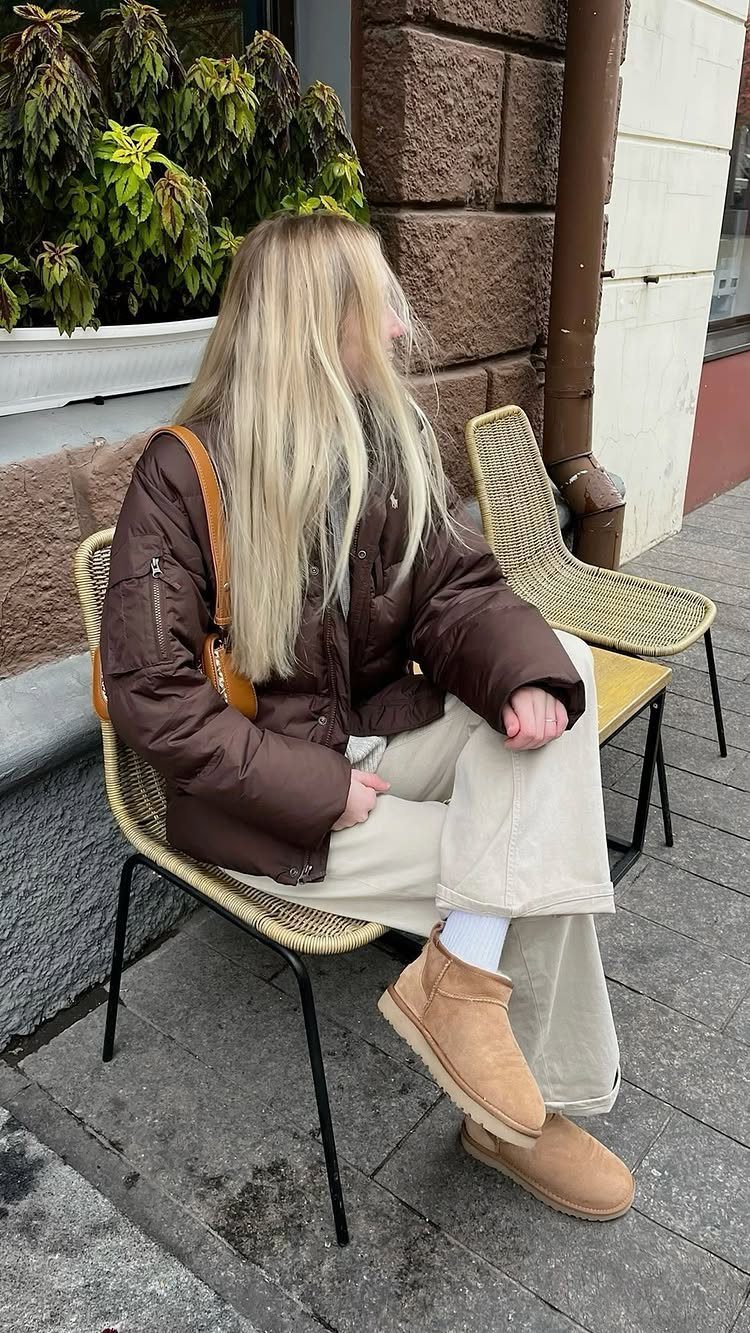 7 Different Types of Uggs for Every Season and Style 1 Woman wearing tan sheepskin ultra mini boots, beige pants, and brown puffer jacket.