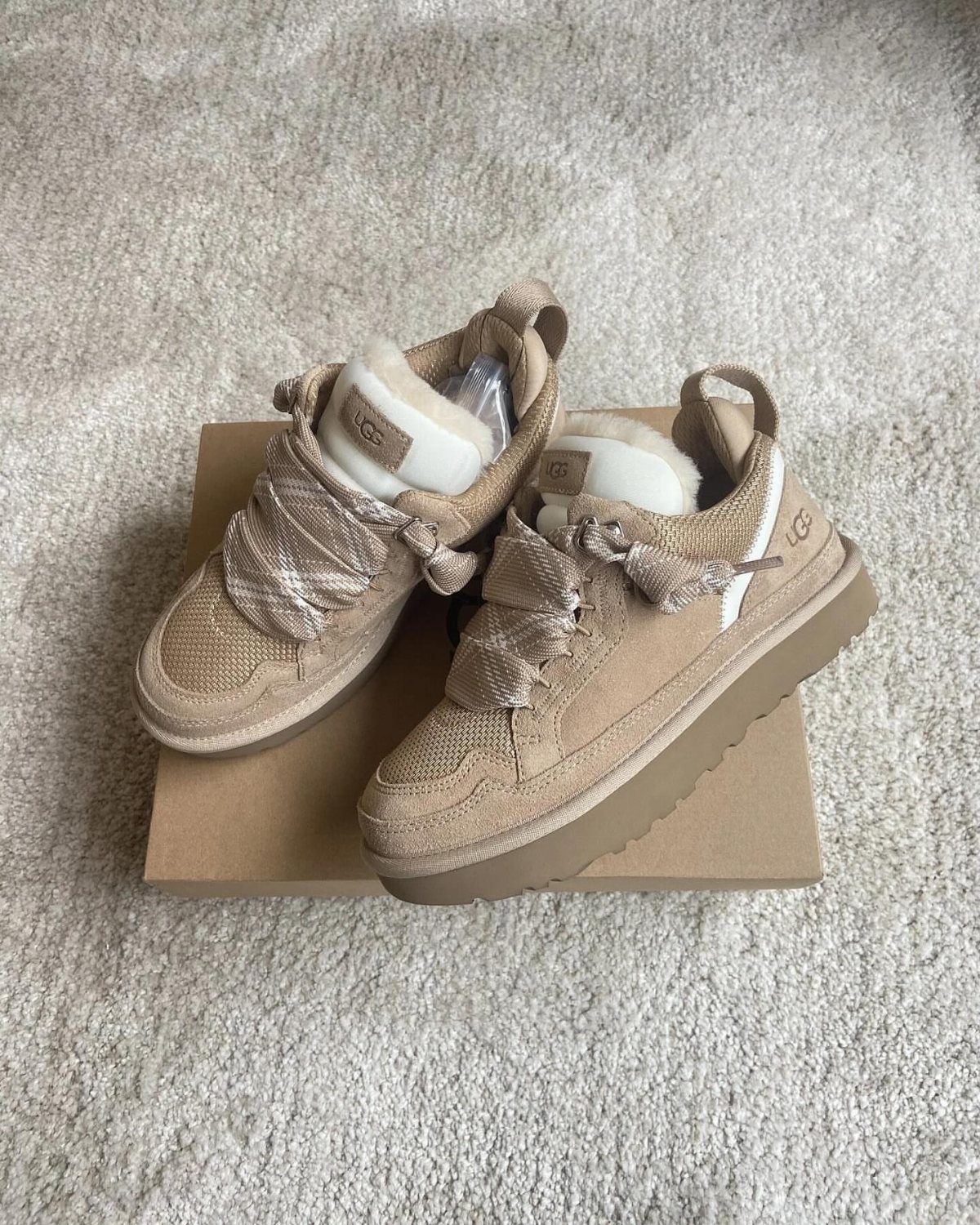 7 Different Types of Uggs for Every Season and Style 3 Tan suede UGG Lowmel trainers with plaid laces on a cardboard box.
