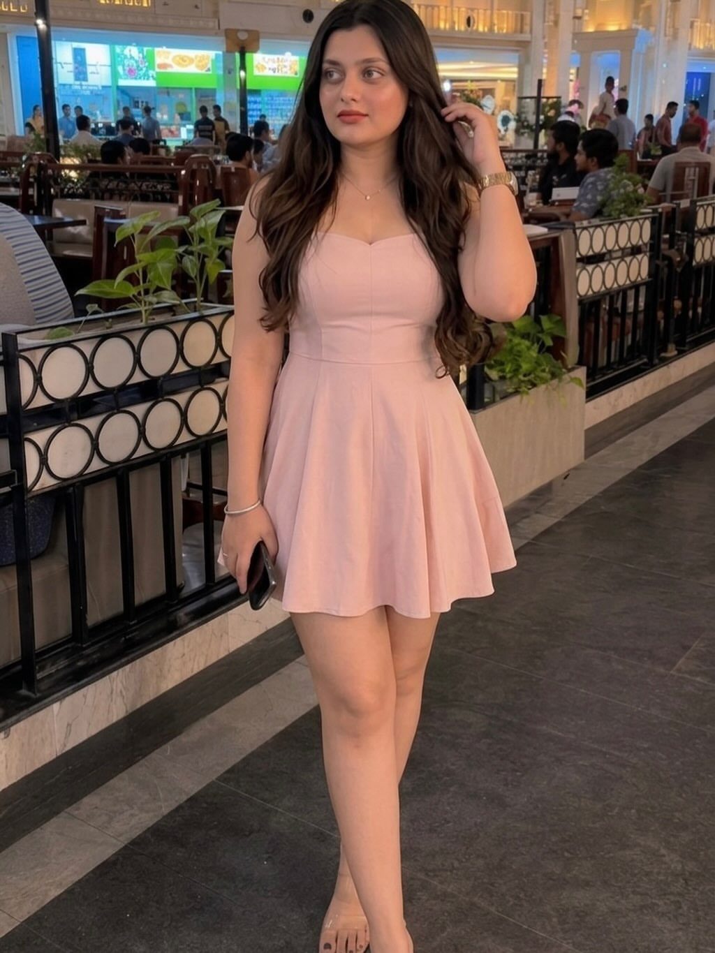 Woman wearing a short light pink sleeveless dress in a modern indoor setting