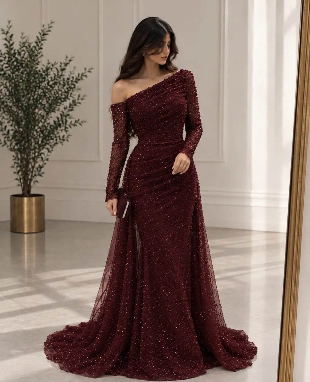6 Elegant Long Sleeve Evening Dress Ideas for Formal Events 5 Woman in a shimmering burgundy long sleeve evening dress standing in a bright room