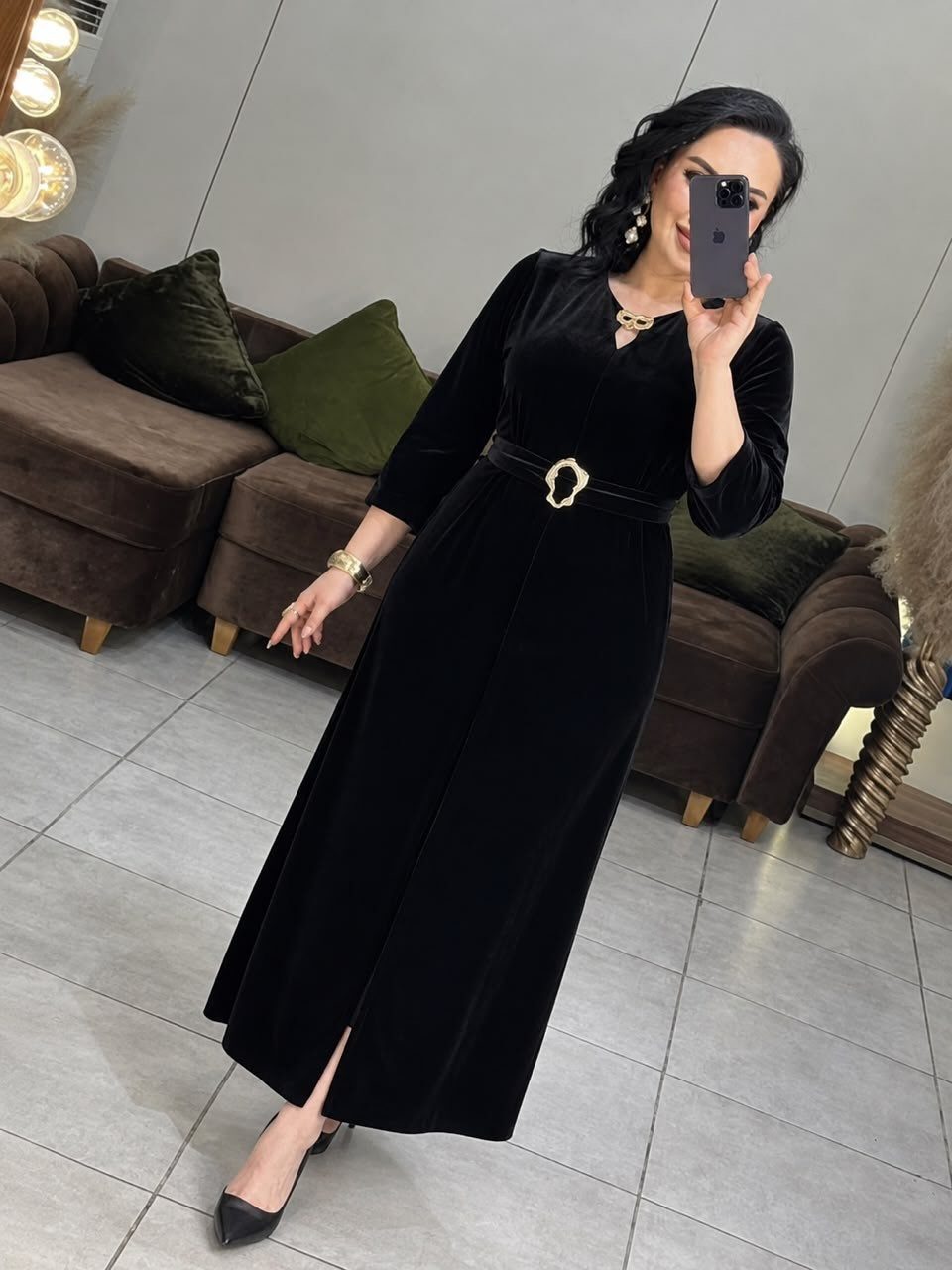 Woman in a floor-length black velvet gown with a gold-buckled belt.