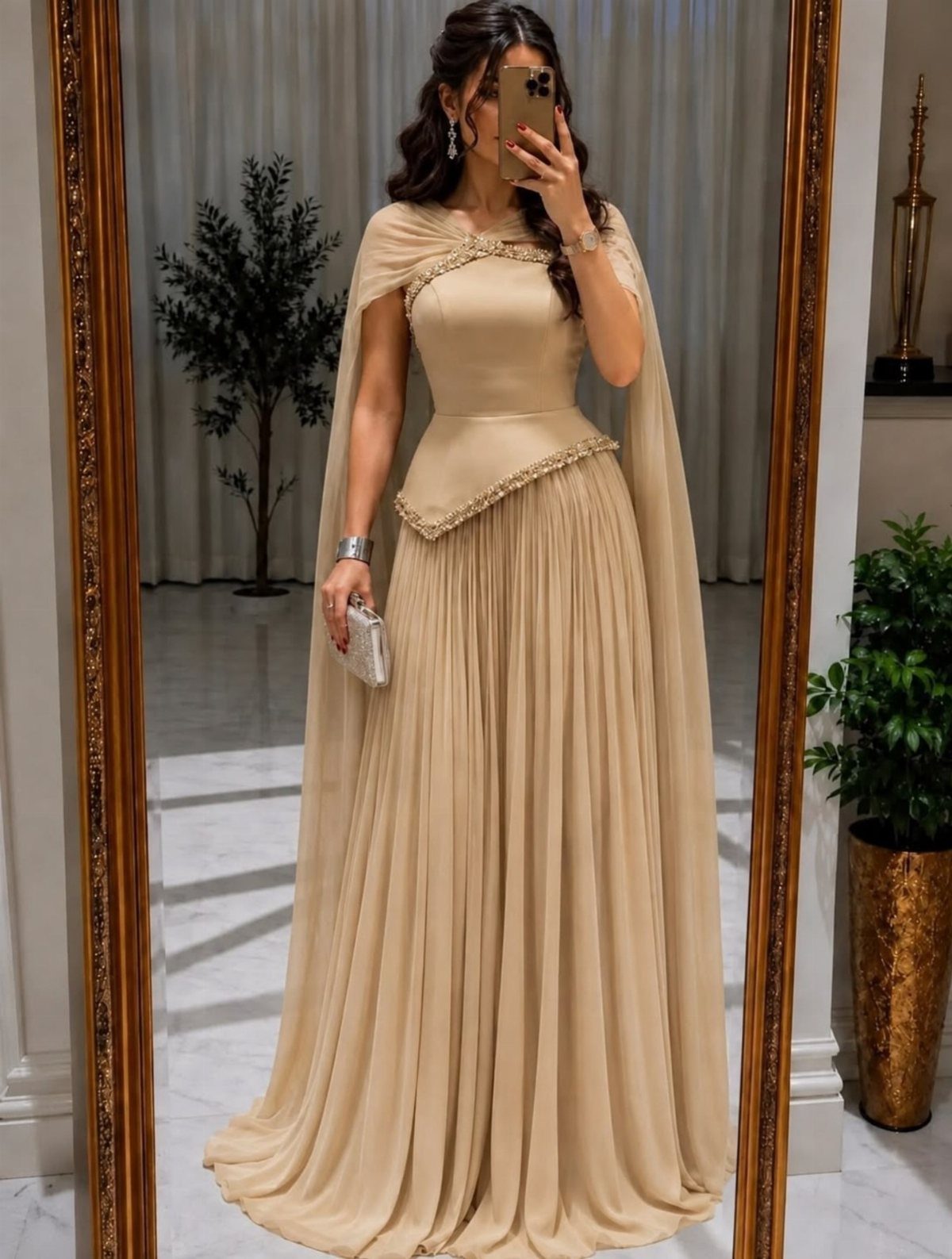 Woman in a champagne flowy maxi dress with cape and beaded accents.