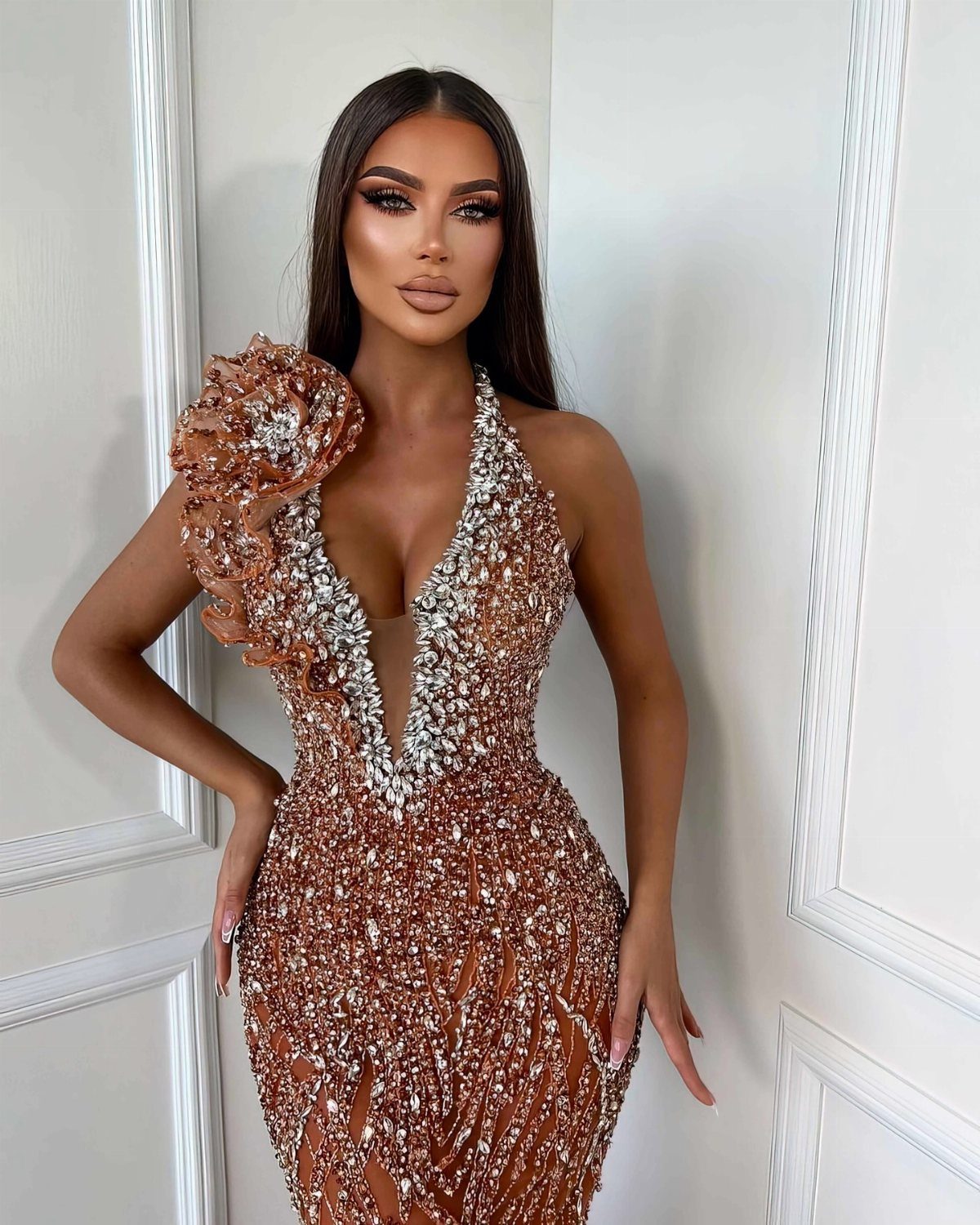 Evening Dress Luxury: 9 Gown Ideas in Satin and Sequins 1 Woman in a shimmering copper embellished evening gown with a floral shoulder detail.