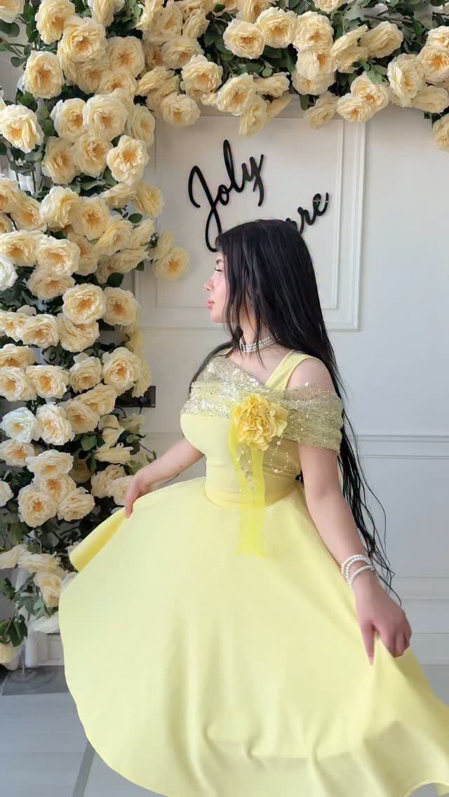 Evening Dress Luxury: 9 Gown Ideas in Satin and Sequins 7 Woman in a yellow ball gown with gold sequins standing by yellow roses.